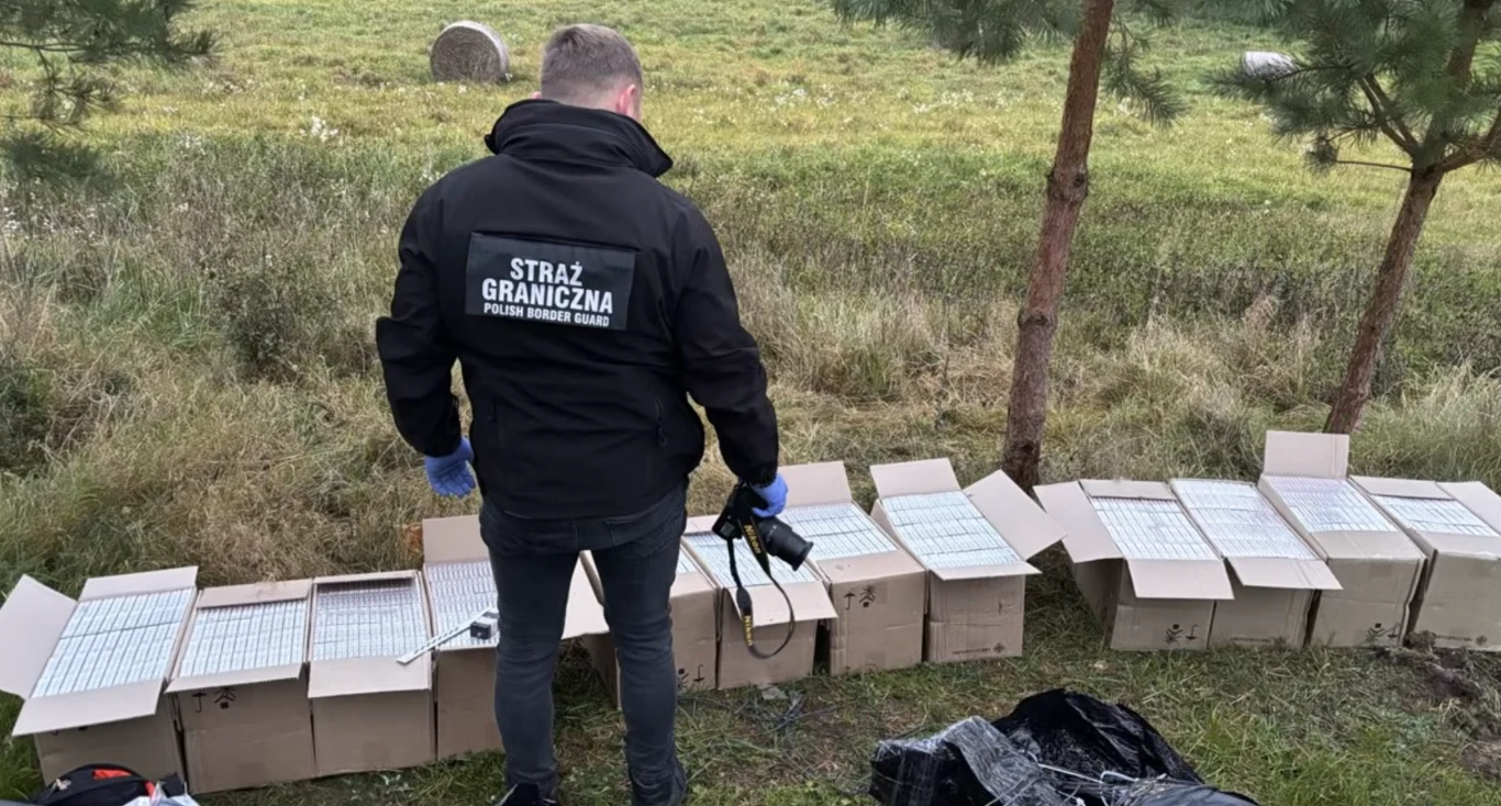 Akcja służb pod Ełkiem. Zabezpieczono nielegalne papierosy. Funkcjonariusz straży granicznej przy zabezpieczonych kartonach z nielegalnymi papierosami w pobliżu Ełku.