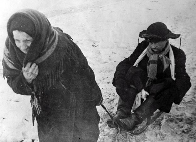 1 lutego 1942 r.: Starsza kobieta wiezie na sankach wyczerpanego głodem mężczyznę /East News