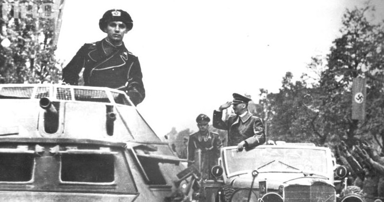 Adolf Hitler w Warszawie pozdrawia z samochodu mercedes salutujących żołnierzy. Na pierwszym planie wóz pancerny SdKfz 222 /Z archiwum Narodowego Archiwum Cyfrowego