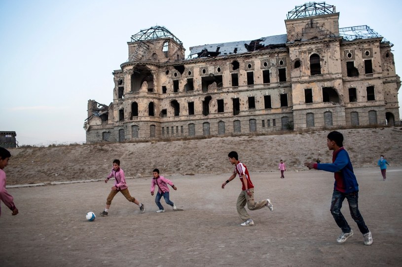 Afgańskie dzieci grające w piłkę przed zniszczonym pałacem /Getty Images/Flash Press Media