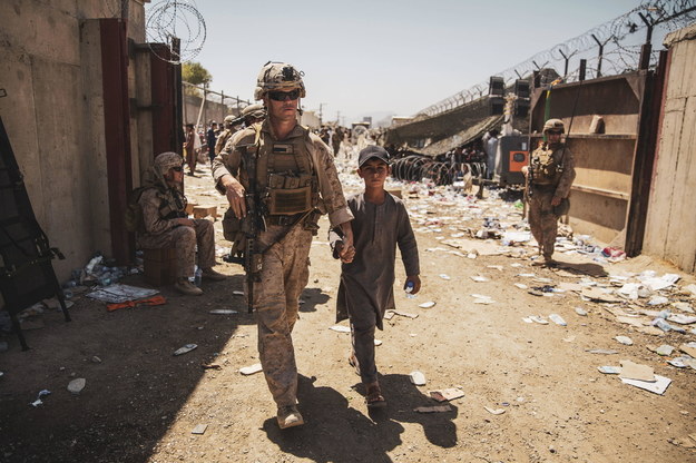 Amerykański żołnierz eskortuje dziecko do jego rodziny podczas ewakuacji na międzynarodowym lotnisku Hamida Karzai w Kabulu w Afganistanie /	Victor Mancilla - US Marine Corps via CNP /PAP/Newscom