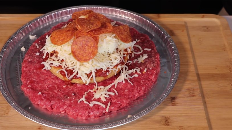 Baza w formie mrożonej pizzy, ogromny kawał mięsa z minipizzą, która za chwilę zostanie przykryta kolejną warstwą mięsa /YouTube