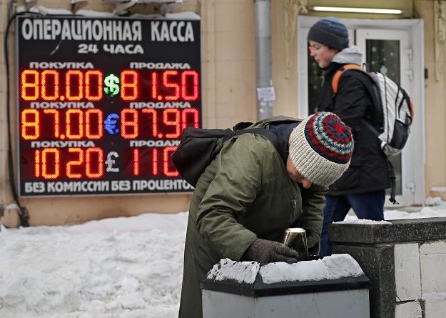 Biedna Rosjanka przeszukuje kosz na śmieci. Z tyłu kantor wymian walut /EPA