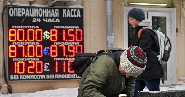 Biedna Rosjanka przeszukuje kosz na śmieci. Z tyłu kantor wymian walut /EPA