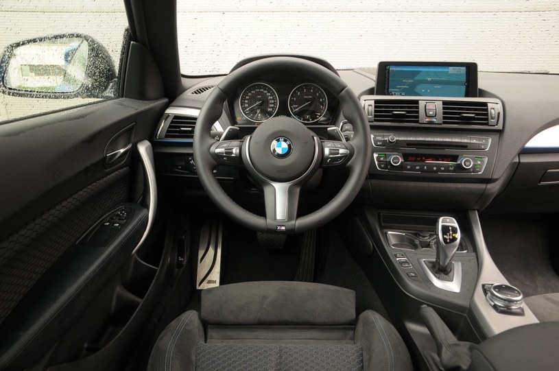 BMW M235i: deska rozdzielcza jest praktycznie identyczna z tą w serii 1. Znakomita sportowa kierownica z logo M to wyposażenie seryjne. Obsługa jest typowa dla wszystkich BMW, czyli wyjątkowo łatwa. Z boku tunelu środkowego znalazła się miękka poduszka, o którą kierowca może oprzeć kolano. /Motor