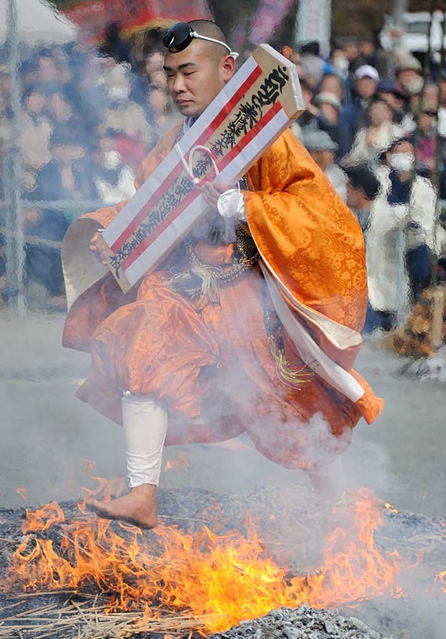 Buddyjski mnich, z talizmanem w rękach, przechodzi gołymi stopami po rozżarzonych węglach, Japonia /AFP