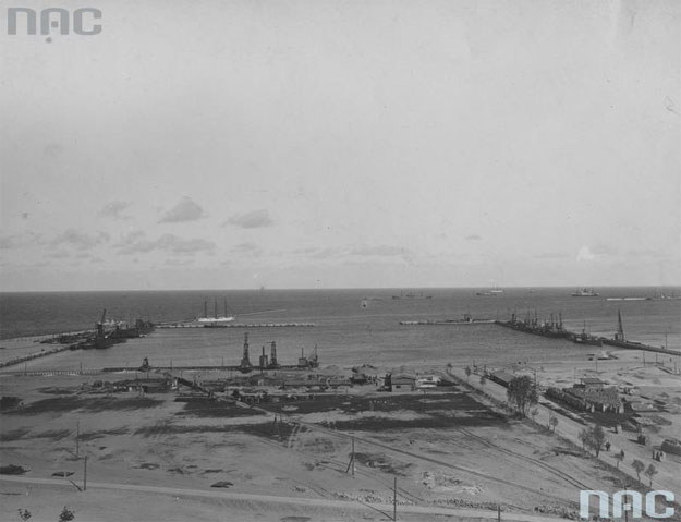 Budowa portu Marynarki Wojennej w Gdyni. Na pierwszym planie widoczne warsztaty portu wojennego, w tle statki na morzu /Z archiwum Narodowego Archiwum Cyfrowego