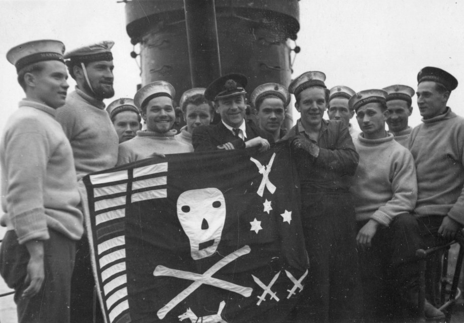 Dowódca ORP Dzik kpt. mar. Bolesław Romanowski z flagą tzw. Jolly Roger, w otoczeniu marynarzy, po powrocie z Morza Śródziemnego, Plymouth 7 IV 1944 r. /Muzeum Marynarki Wojennej w Gdyni / FB /Facebook