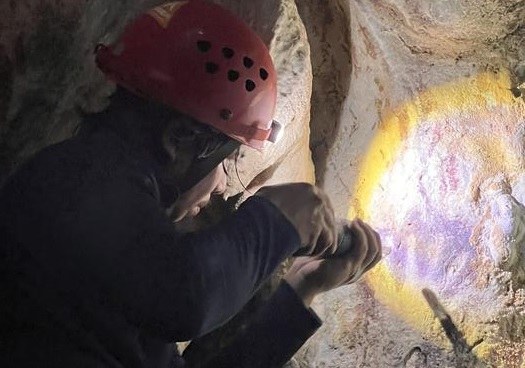 Dr Adhi Agus Oktaviana oświetla inny ślad dłoni w jaskini /Fot. Max Aubert /Materiały prasowe