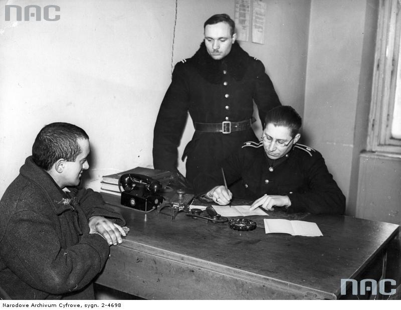 Dwaj polscy policjanci podczas przesłuchiwania w komisariacie w Krakowie zatrzymanego mężczyzny, 1940 /Z archiwum Narodowego Archiwum Cyfrowego