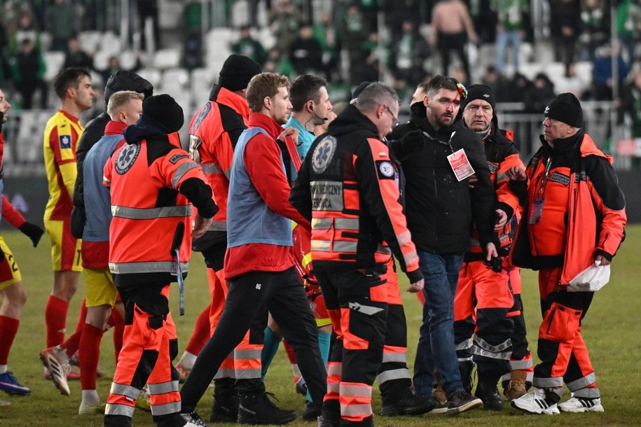 Dyrektor komunikacji i marketingu Korony Kielce Michał Siejak z rozciętą głową wyprowadzany przez ratowników medycznych. /Piotr Polak