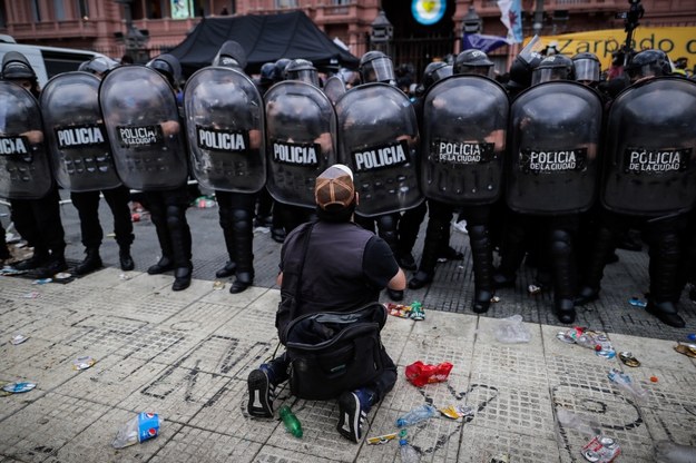 Fan Diego Maradony klęczy przed policją, która zabezpiecza miejsce przed Casa Rosada /JUAN IGNACIO RONCORONI /PAP/EPA