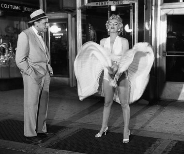 Fani Marilyn Monroe z pewnością pamiętają również kultową suknię przygotowaną przez kostiumografa Williama Travilla, w której gwiazda zaprezentowała się w filmie "Słomiany wdowiec". Postać grana przez Monroe uchwycona w zjawiskowej stylizacji z białą sukienką uniesioną przez podmuch powietrza z kanału wentylacyjnego metra to bezsprzecznie jeden z najbardziej stylowych momentów w historii kina. Wiązana na szyi kreacja z odważnym dekoltem mocno podkreślała talię i eksponowała nogi, stając się z miejsca najmodniejszym fasonem lat 50., wielokrotnie powielanym przez rozmaitych projektantów. Każda kobieta chciała wówczas wyglądać jak Marilyn - blondwłosa piękność w zmysłowych, rozkloszowanych sukienkach i diamentowej biżuterii.