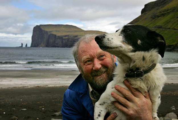 Farmer bawi się z psem niedaleko wsi Tjoernuvik na wyspie Streymoy /AFP