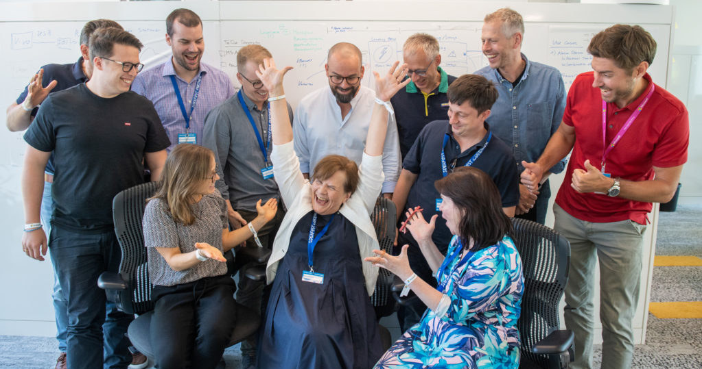 Felicitas Hanne z radością podnosi ręce, otoczona przez niektórych członków zespołu Microsoft Germany, który opracował rozwiązania dla Kinderhaus AtemReich. Zdjęcie: Microsoft /materiały prasowe