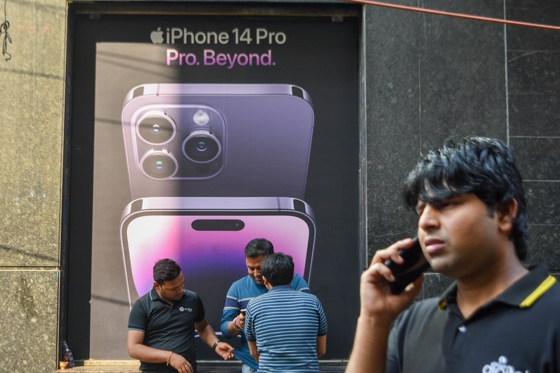 Firma Foxconn, producent iPhone'ów, planuje otworzyć fabrykę urządzeń Apple w Indiach. Docelowo chce do tego kraju przenieść nawet do 25 proc. mocy produkcyjnych. / Zdjęcie przedstawia mężczyzn na tle reklamy iPhone'a 14 Pro w Kalkucie (Indie). /DEBARCHAN CHATTERJEE NurPhoto NurPhoto przez AFP /AFP