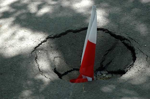 Flaga Polski wlozona do dziury w jezdni. Fot. Jacek Rajkowski /Informacja prasowa
