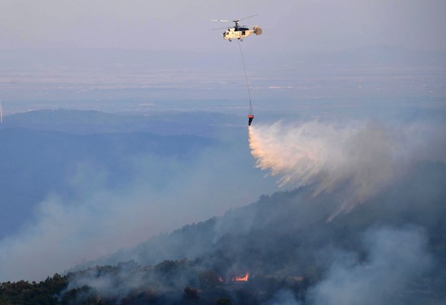 Helikopter strażacki zrzuca wodę podczas gaszenia pożaru w rejonie miejscowości Leptokaria w północnej Grecji. /DIMITRIS ALEXOUDIS /PAP/EPA