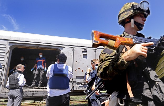 Holenderscy inspektorzy w pociągu, w którym złożone są ciała ofiar katastrofy. Na pierwszym planie: uzbrojony separatysta /ROBERT GHEMENT /PAP/EPA