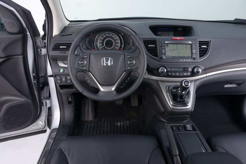 Honda CR-V 2.2 i-DTEC Executive: przemyślany, uporządkowany i łatwy w obsłudze kokpit. Dźwignia zmiany biegów jest w idealnym miejscu. Po jej bokach zamontowano miękkie poduszki, dzięki którym nie trzeba opierać kolan o twardy plastik. Nawigacja wymaga dopłaty, kamera cofania (ekran nad nią) jest seryjna. /Motor