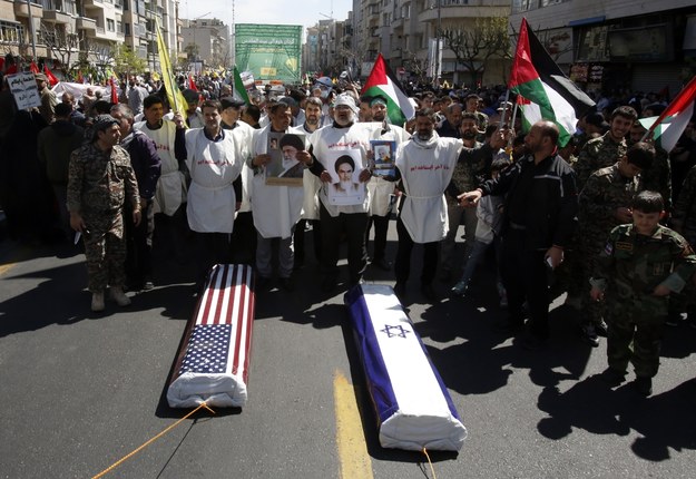 Irańczycy ciągną trumny owinięte we flagi USA i Izraela podczas wiecu w Teheranie /Abedin Taherkenareh   /PAP/EPA