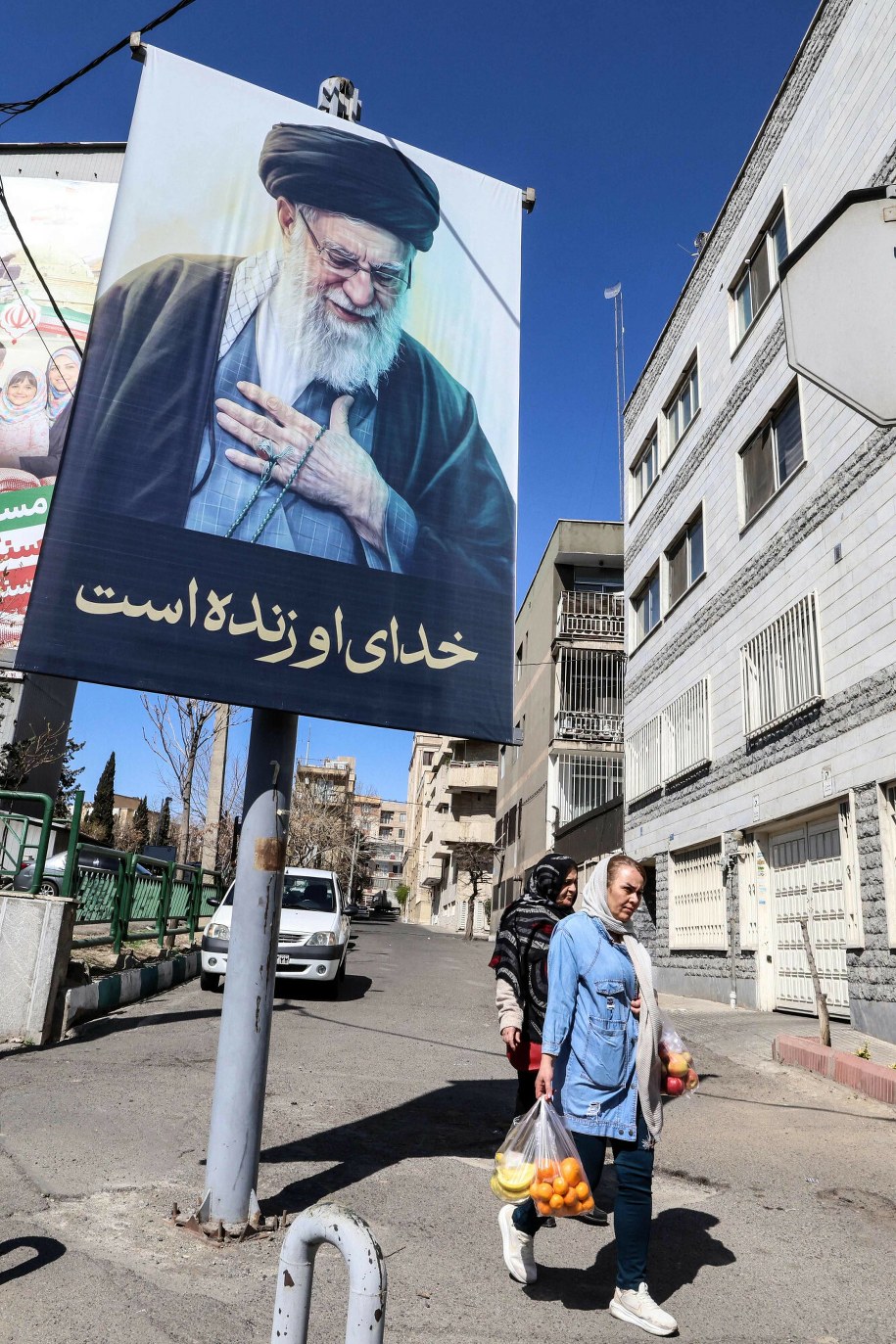 Irańczycy przechodzą obok portretu zabitego najwyższego przywódcy Iranu, ajatollaha Alego Chameneiego, z napisem po persku "Jego Bóg wciąż żyje" /-/AFP/East News /East News