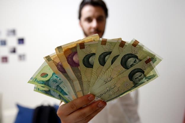 Irańczyk z banknotami lokalnej waluty (rialami) /EPA