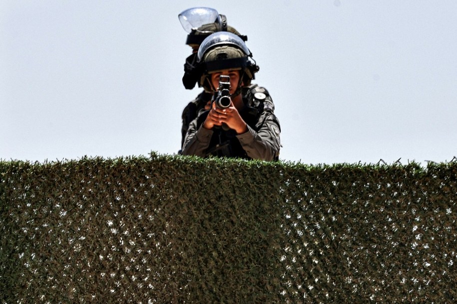 Izraelski strażnik graniczny patrzy przez lunetę karabinu podczas wyburzania budynku w wiosce Judeira na okupowanym Zachodnim Brzegu. 04.08.2025 r. /ZAIN JAAFAR/AFP /East News