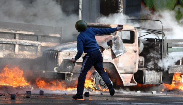 Jeden z protestujących w Kijowie przy płonącym samochodzie /PAP/EPA/IGOR KOVALENKO /PAP/EPA