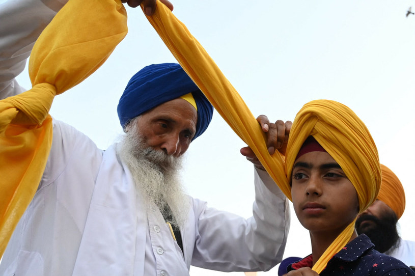 Kapłan sikhijski zawiązuje turban wokół głowy chłopca podczas obchodów "Dnia Turbana", w Amritsar 13 kwietnia 2023 r. (Foto Narinder NANU / AFP) /East News