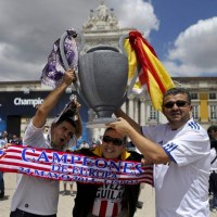 Kibice Realu Madryt i Atletico Madryt trzymają trofeum. 