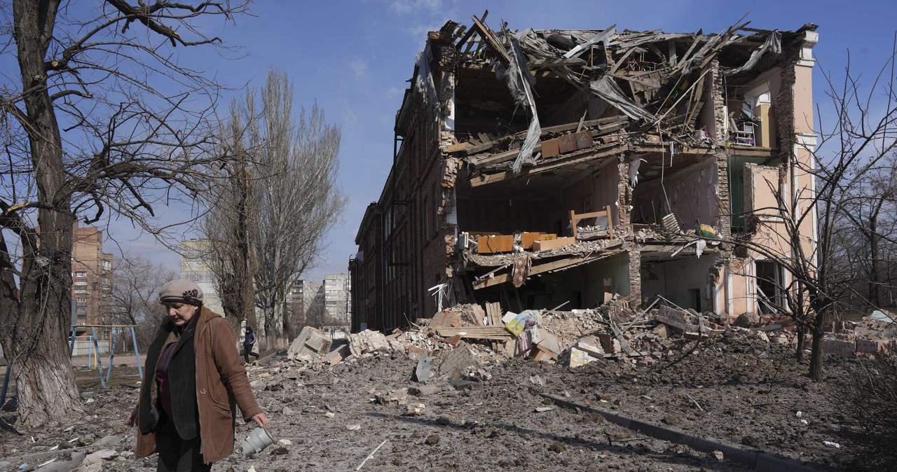 Kobieta na tle budynku zniszczonego przez ostrzał w Mariupolu /Associated Press /East News
