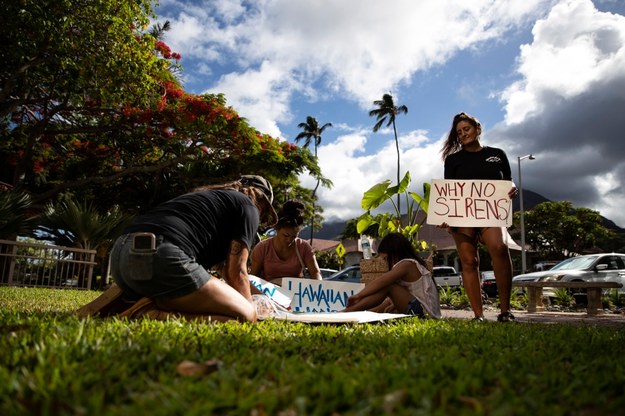 Kobieta protestująca na Hawajach z transparentem "dlaczego nie ma syren?". /ETIENNE LAURENT /PAP/EPA