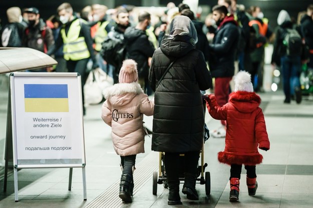 Kobieta z dwójką dzieci i wózkiem dziecięcym przechodzi obok drogowskazu z napisem „dalsza podróż” po przybyciu pociągów z uchodźcami z granicy ukraińsko-polskiej na berliński dworzec główny Hauptbahnhof /Clemens Bilan /PAP/EPA