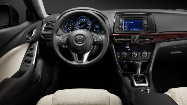 Kokpit ma architekturę znaną z modelu CX-5, z zegarami w tubach i 5-calowym ekranem pokładowej telematyki. Nowością jest pas ciemnoczerwonego tworzywa, biegnący przez front deski rozdzielczej. /Mazda