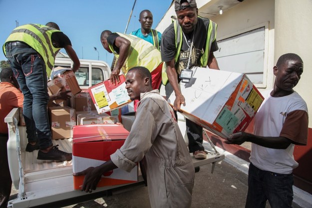 Liberyjczycy rozładowują transport ochronnych ubrań i materiałów edukacyjnych nt. wirusa Ebola /AHMED JALLANZO  /PAP/EPA
