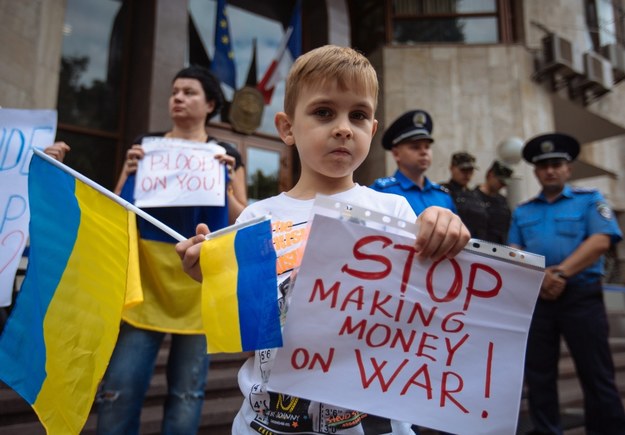 Lipiec 2014, demonstracja przed ambasadą Francji w Kijowie przeciwko sprzedaży Rosjanom okrętów Mistral. Chłopiec trzyma ukraińską flagę i kartkę z napisem "Przestańcie zarabiać na wojnie!" /ROMAN PILIPEY /PAP/EPA