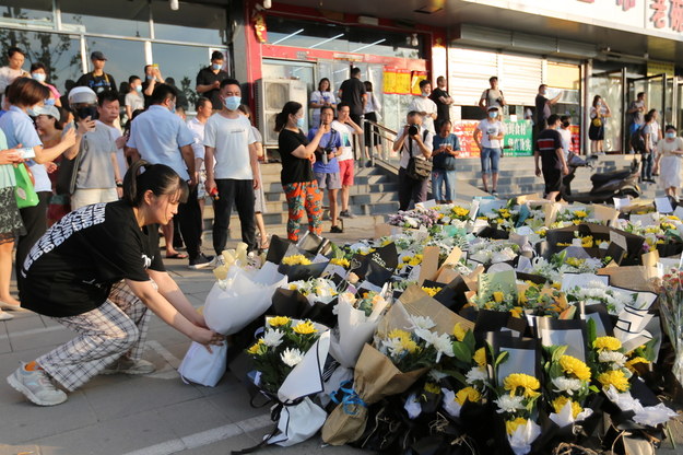 Ludzie składają kwiaty pod stacją metra, gdzie podczas powodzi zginęło 14 osób /YU HONGEN /PAP/EPA