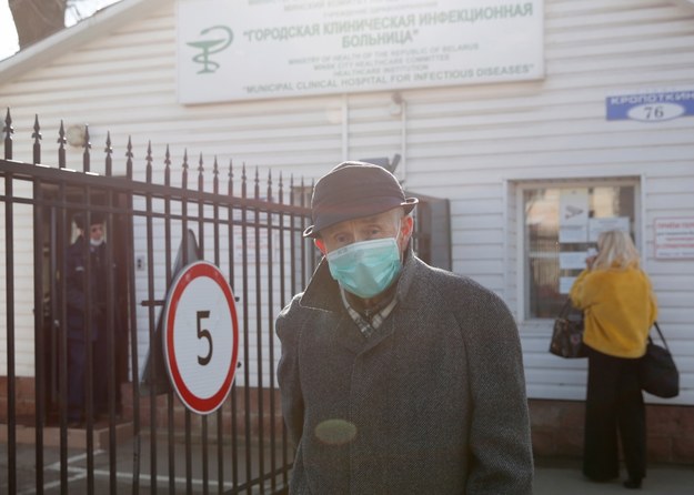 Mężczyzna w medycznej masce na twarzy stoi przy bramie szpitala chorób zakaźnych w Mińsku na Białorusi /TATYANA ZENKOVICH  /PAP/EPA