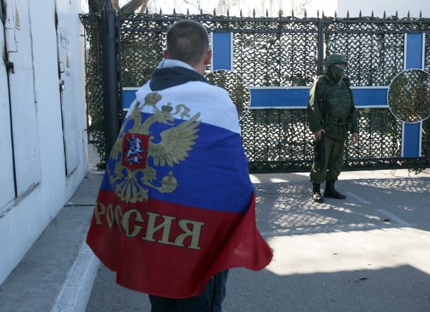 Mężczyzna z rosyjską flagą przed kwaterą marynarki w Sewastopolu /PAP/EPA/ZURAB KURTSIKIDZE /PAP/EPA