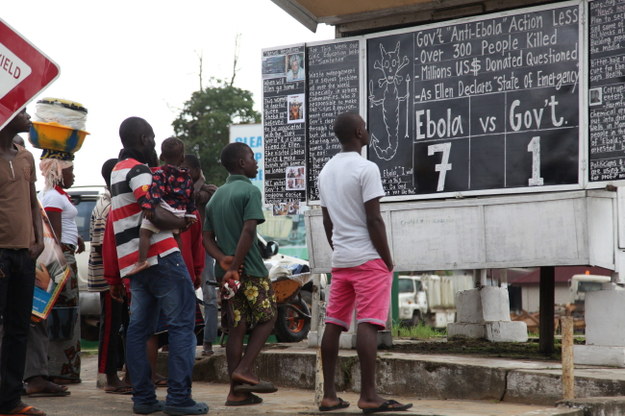 Mieszkańcy liberyjskiej Monrovii przy tablicy informacyjnej dot. eboli /PAP/EPA/AHMED JALLANZO /PAP/EPA