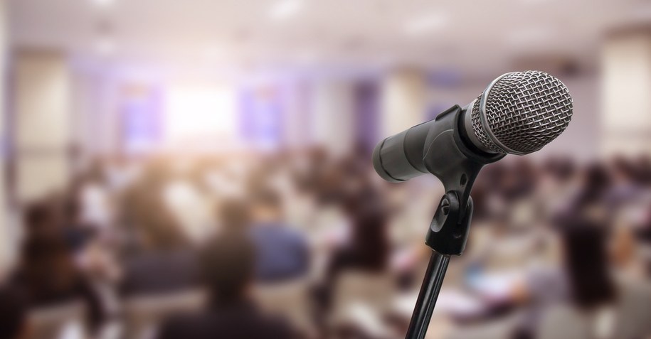 Mikrofon na tle wypełnionej sali /Shutterstock