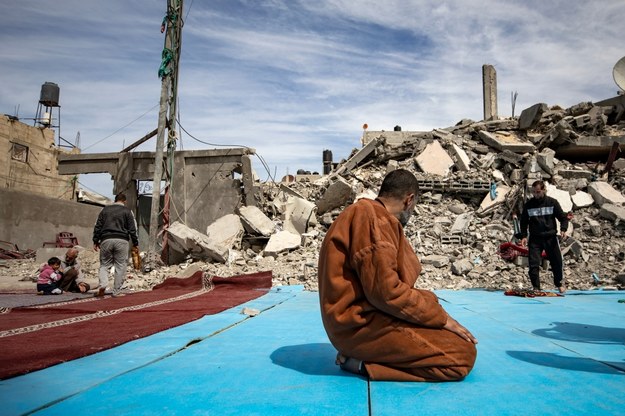 Młody mężczyzna modlący się wśród ruin zbombardowanej Strefy Gazy /HAITHAM IMAD /PAP/EPA