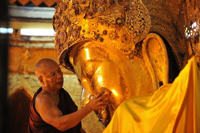 Mnich czyści pozłacany posąg Buddy w świątyni w Mandalay /AFP