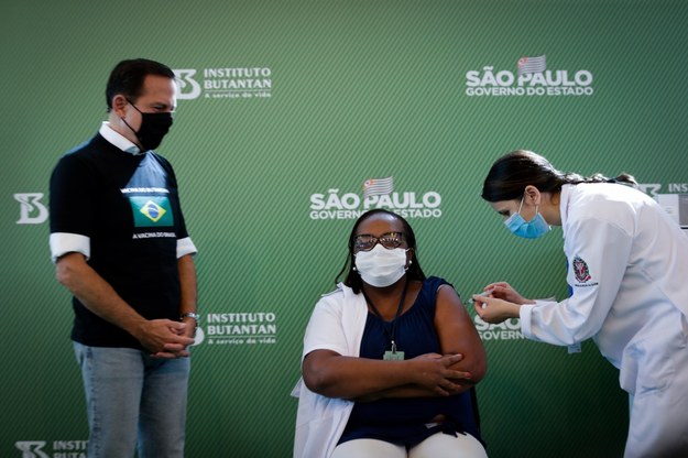 Monica Calazans (C), pielęgniarka w Hospital las Clinicas w stolicy Sao Paulo, otrzymuje szczepionkę przeciwko COVID-19 w obecności gubernatora stanu Sao Paulo, Joao Doria (L), w Sao Paulo w Brazylii /FERNANDO BIZERRA JR. /PAP/EPA