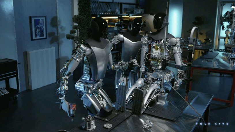 Najnowsza wersja robotów Tesli potrafi naprawiać inne roboty. Na zdjęciu jeden z robotów Optimus poprawia mocowanie ramienia innego robota /East News