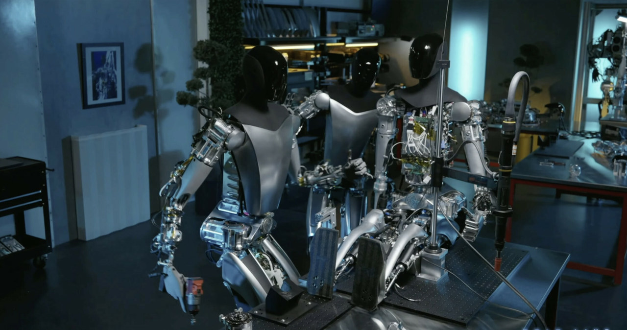 Najnowsza wersja robotów Tesli potrafi naprawiać inne roboty. Na zdjęciu jeden z robotów Optimus poprawia mocowanie ramienia innego robota /East News