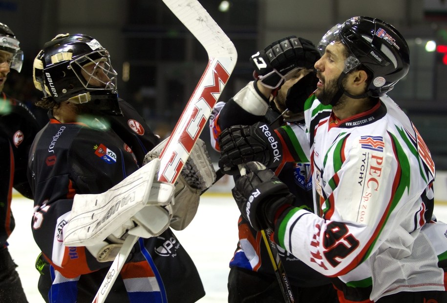 Napastnik GKS-u Tychy Mikołaj Łopuski (po prawej) w starciu z bramkarzem Ciarko PBS Bank KH Sanok Johnem Murrayem podczas pierwszego meczu finałowego fazy play off Polskiej Hokej Ligi /Andrzej Grygiel /PAP