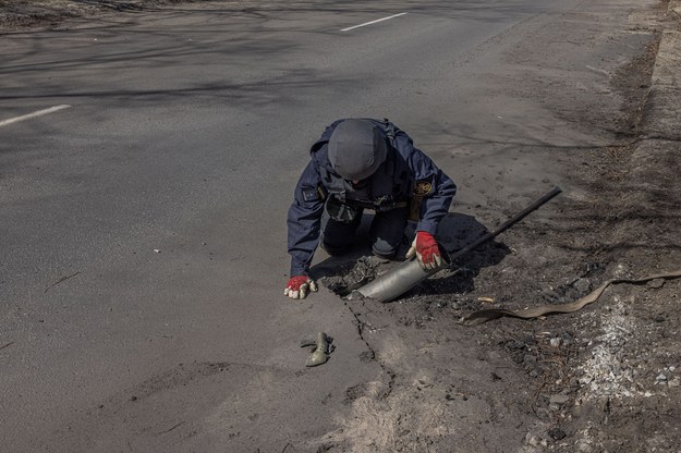 Ołeksandr Gumenczak, saper Państwowej Służby Ratunkowej Ukrainy usuwa metalowy kawałek rakiety Grad, który utknął na drodze po rosyjskim ataku, na obrzeżach Charkowa /ROMAN PILIPEY /PAP/EPA