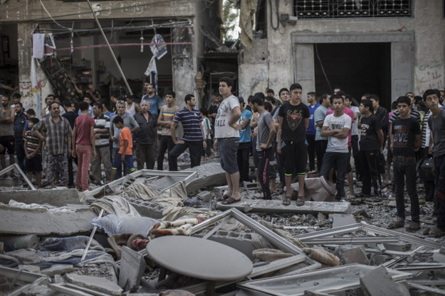 Palestyńczycy na ruinach budynku zniszczonego podczas izraelskiego nalotu /Oliver Weiken /PAP/EPA